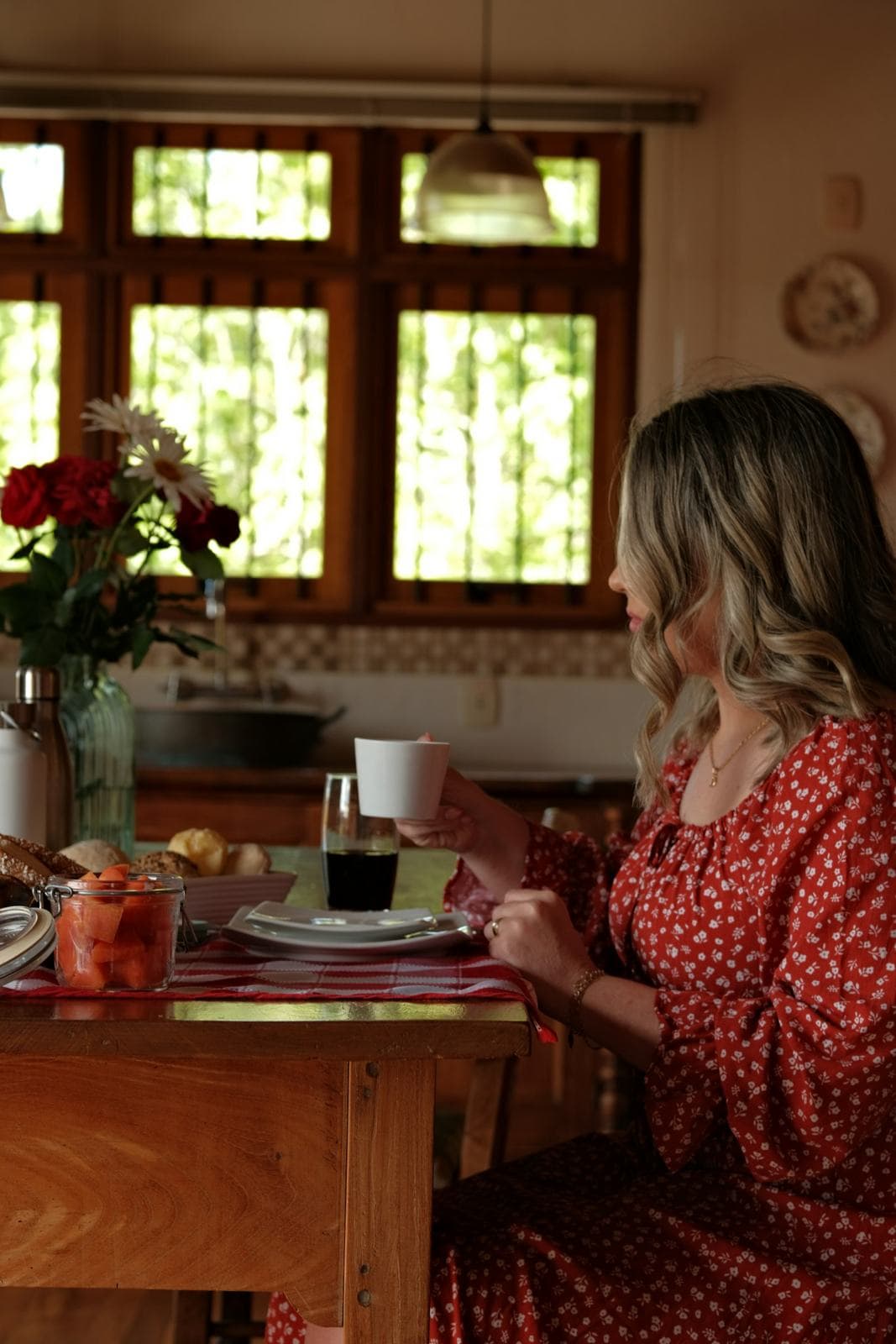 A woman at her kitchen table with a cup of coffee, in morning light